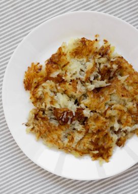 Beyaz bir tabakta ev yapımı kızarmış Hashbrowns, üst manzara. Dümdüz, tepeden, yukarıdan.