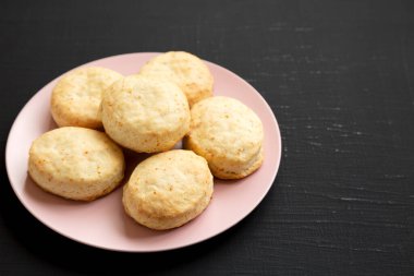 Siyah arka planda pembe bir tabakta ev yapımı Flaky Buttermilk Bisküvileri. Boşluğu kopyala.