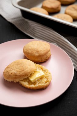 Siyah arka planda pembe bir tabakta ev yapımı Flaky Buttermilk Bisküvileri.. 
