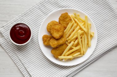 Lezzetli Fast food: Tavuk nugget ve patates kızartması beyaz ahşap bir masada tabakta, üst manzara. Dümdüz, tepeden, yukarıdan. 