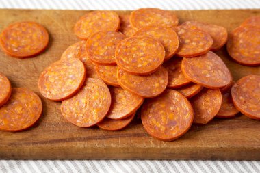İtalyan Pepperoni Dilimleri kumaş üzerinde ahşap bir tahta üzerinde, düşük açılı. Yakın plan..