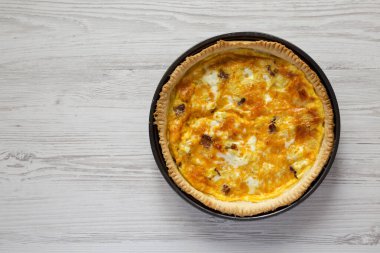 Beyaz ahşap bir yüzey üzerinde yumurta ve çedar peynirli ev yapımı pastırmalı kiş. Dümdüz yatıyordu, yukarıdan, yukarıdan. Metin için boşluk.