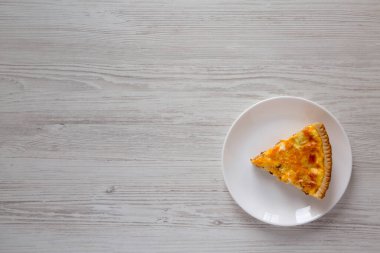 Beyaz ahşap arka planda yumurta ve çedar peynirli ev yapımı pastırmalı kiş. Boşluğu kopyala.