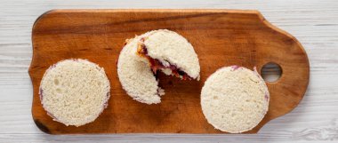 Ev yapımı kabuksuz fıstık ezmesi ve jöleli halkalar beyaz ahşap arka planda, ahşap bir tahta üzerinde, üst manzara. Dümdüz, tepeden, yukarıdan. 