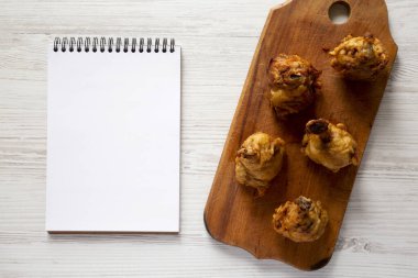 Ev yapımı Baharatlı Tavuk Lolipopu, ahşap bir tahtanın üzerinde, boş not defteri, üst manzara. Yukarıdan, dümdüz uzanmış.