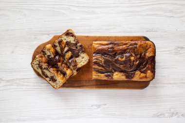 Beyaz ahşap bir masanın üstünde, muz ekmekli ev yapımı çikolatalı ekmek. Dümdüz, tepeden, yukarıdan. 