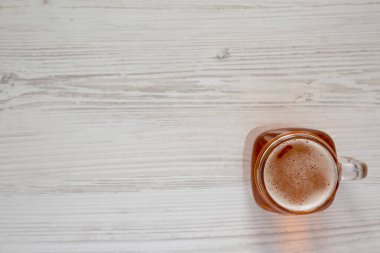 Cam kavanoz bardakta sert elma birası, beyaz ahşap bir masada, üst manzara. Dümdüz, tepeden, yukarıdan. Boşluğu kopyala.