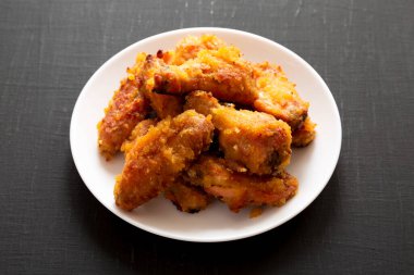 Siyah arka planda beyaz tabakta ev yapımı Baharatlı Tavuk Kanatları.. 