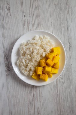 Mangolu ev yapımı pilav ve beyaz tahta bir masada beyaz bir tabakta susam tohumu, üst manzara. Dümdüz, tepeden, yukarıdan.