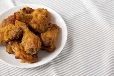 Ev yapımı baharatlı tavuk kanatları beyaz bir tabakta, yan görünüşte. Metin için boşluk.