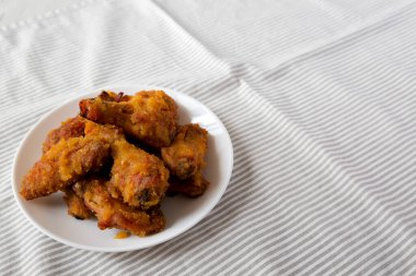 Ev yapımı Baharatlı Tavuk Kanatları beyaz bir tabakta, düşük açılı. Boşluğu kopyala.