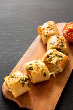 Ev yapımı parmesanlı tavuk sarımsaklı ekmek siyah arka planda, ahşap bir tahta üzerinde. Boşluğu kopyala.