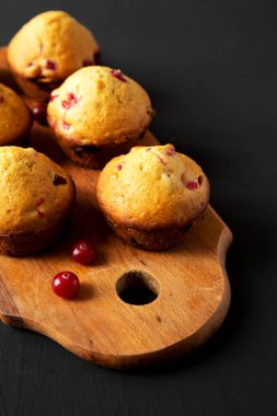 Siyah arka planda, portakal aromalı ev yapımı kızılcık çörekleri ve ahşap bir tahta. Metin için boşluk.