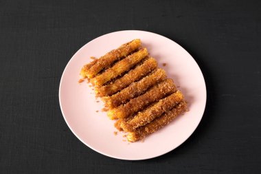 Ev yapımı Churro Isırıkları siyah arka planda pembe bir tabakta, yan manzarada.
