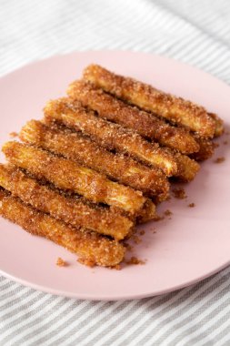 Ev yapımı Churro Isırıkları pembe bir tabakta, yan manzaralı. Yakın plan..