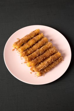 Ev yapımı Churro Isırıkları, pembe bir tabakta, siyah bir yüzey üzerinde..