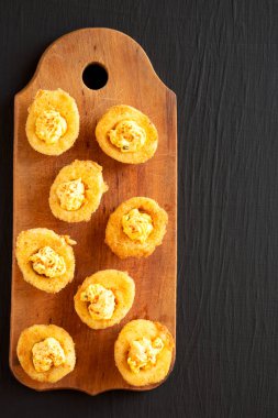 Kırmızı paprikalı ev yapımı, yağda kızartılmış yumurtalar siyah arka planda, ahşap bir tahta üzerinde, üst manzara. Dümdüz, tepeden, yukarıdan. Boşluğu kopyala.