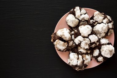 Siyah arka planda pembe bir tabakta ev yapımı çikolatalı buruşuk kurabiyeler. Yukarıdan, dümdüz yatıyordu. Boşluğu kopyala.