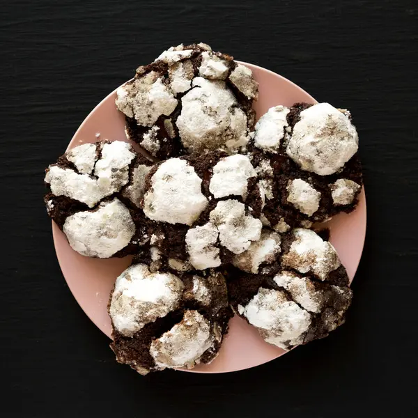Hausgemachte Chocolate Crinkle Cookies Auf Einem Rosa Teller Auf Schwarzem — Stockfoto
