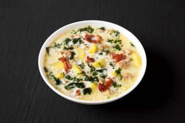 Ev yapımı Zuppa Toscana Kale ve Ekmek ile siyah arka planda beyaz bir kasede, yan görünümde..