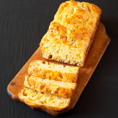 Ev yapımı Peynirli Ekmek Siyah bir yüzey üzerinde ahşap bir tahta üzerinde, düşük açılı. 