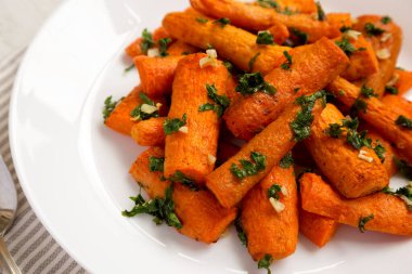 Beyaz tabakta otlu ev yapımı kızarmış havuç, düşük açılı. Yakın plan..