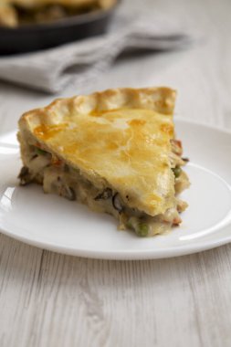 Beyaz bir tabakta beyaz bir tavuklu börek, ahşap arka planda, yan görünüşte..