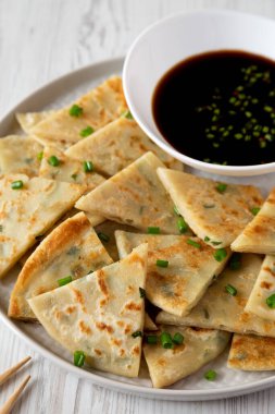 Homemade Scallion Pancakes with Soy Dipping Sauce on a white wooden background, side view. 