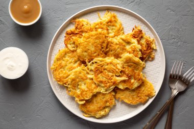 Homemade Potato Pancakes Latkes with Apple Sauce and Sour Cream on a gray background, top view. Flat lay, overhead, from above. 