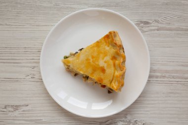 A Piece of Chicken Pot Pie on a white plate on a white wooden background, top view. Flat lay, overhead, from above. 