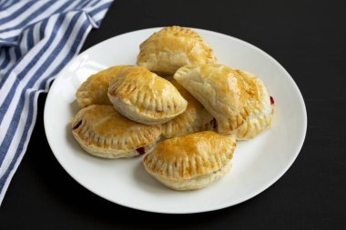 El yapımı vişneli turtalar, siyah bir tabakta, yan görünüşte..