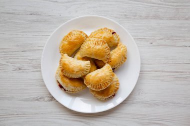 Beyaz ahşap arka planda beyaz bir tabakta el yapımı vişneli turtalar. Üst manzara, yukarıdan, düz yatıyordu.. 