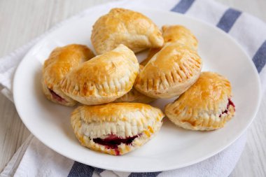 Beyaz ahşap arka planda beyaz bir tabakta el yapımı vişneli turtalar. Yakın plan..