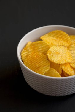 Siyah bir yüzey üzerinde fırfırlı peynirli patates cipsi.. 