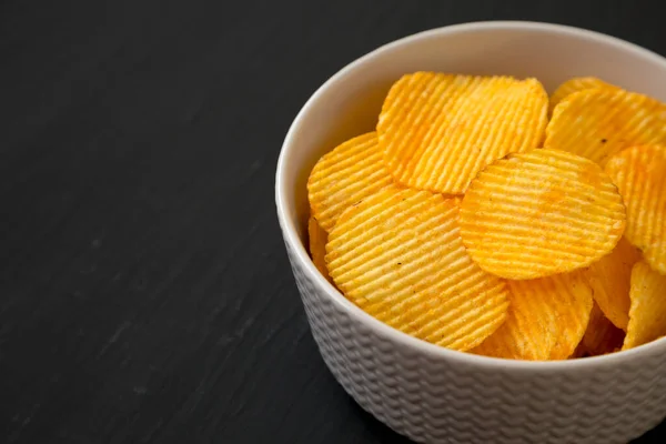 Ruffled Cheese Potato Chips Een Schaal Een Zwart Oppervlak Zijaanzicht — Stockfoto
