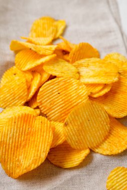 Fırfırlı Peynirli Patates cipsi bir kase içinde kumaş üzerinde, yan görüş.
