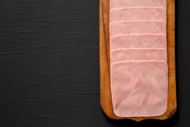 Siyah arka planda, kırsal tahta üzerinde organik Jamon Cocido Extra, üst manzara. Dümdüz, tepeden, yukarıdan. Boşluğu kopyala.