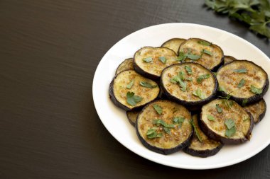 Siyah bir yüzeyde beyaz bir tabakta ev yapımı organik fırınlanmış patlıcan. Boşluğu kopyala.