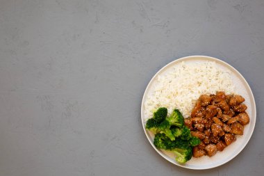 Ev yapımı Teriyaki tavuğu, üstünde pirinç ve brokoli olan gri bir tabakta, üst manzara. Dümdüz, tepeden, yukarıdan.