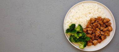 Ev yapımı Teriyaki tavuğu, üstünde pirinç ve brokoli olan gri bir tabakta, üst manzara. Dümdüz, tepeden, yukarıdan. Boşluğu kopyala.