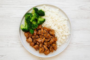 Beyaz ahşap bir yüzey üzerinde pirinç ve brokoli kaplı ev yapımı Teriyaki tavuğu. Dümdüz, tepeden, yukarıdan.