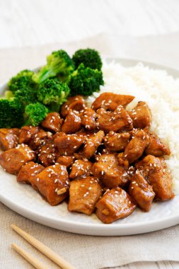 Beyaz ahşap bir yüzey üzerinde pirinç ve brokoli kaplı ev yapımı Teriyaki tavuğu. Yakın plan..