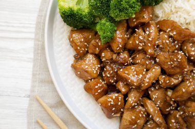 Beyaz ahşap arka planda, üzerinde pirinç ve brokoli olan ev yapımı Teriyaki tavuğu. Dümdüz, tepeden, yukarıdan.