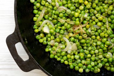 Ev yapımı Sauteed Green Bezelyeleri dökme demir bir tavada, üst manzara. Dümdüz, tepeden, yukarıdan. Yakın plan..