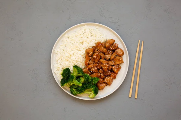 Ev yapımı Teriyaki tavuğu, üstünde pirinç ve brokoli olan gri bir tabakta, üst manzara. Dümdüz, tepeden, yukarıdan. Metin için boşluk.