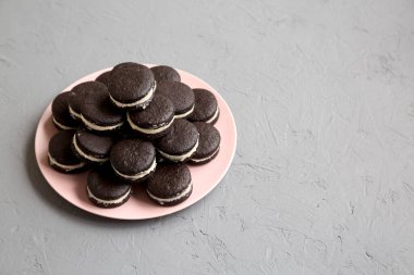 Gri arka planda pembe bir tabakta ev yapımı Oreo 'lar. Düşük açılı. Boşluğu kopyala.