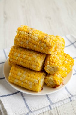 Beyaz ahşap arka planda beyaz bir tabakta ev yapımı tereyağlı parmesan mısır.. 