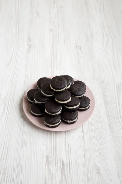 Hausgemachte Oreos Auf Rosa Teller Auf Weißem Holzhintergrund Seitenansicht — Stockfoto