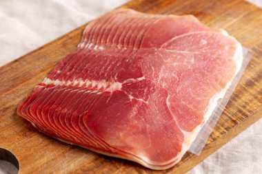 Ahşap bir tahtanın üzerinde İştah açıcı Jamon Serrano dilimleri..