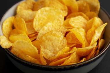 Siyah arka planda bir kasede kızarmış patates cipsi, yan görüş. Yakın plan..